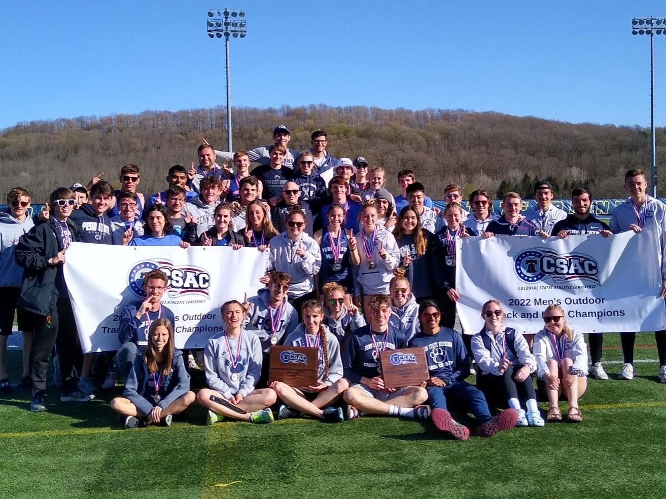 Penn State Behrend's track and field teams pose with the CSAC championship banners.
