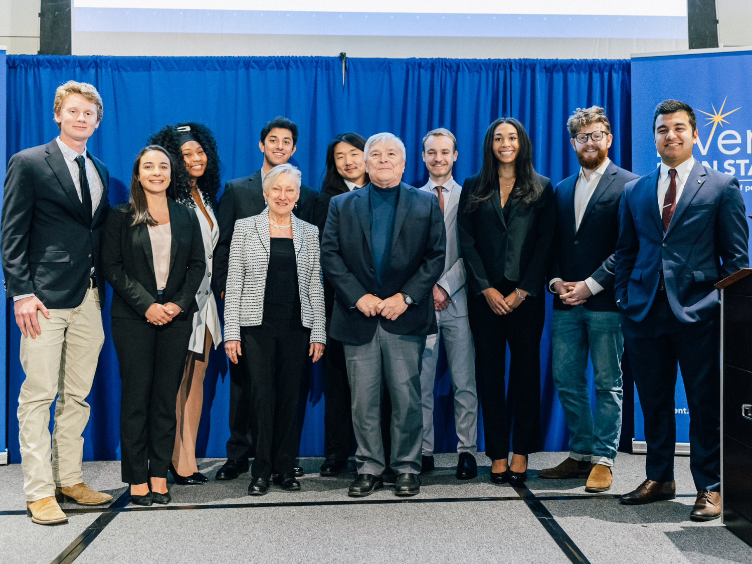 Student founders standing with President Eric Barron on stage