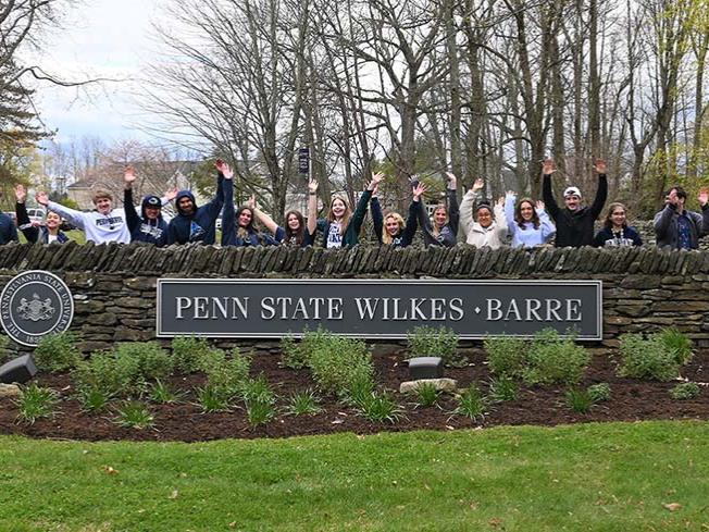 People standing behind the Penn State Wilkes-Barre sign