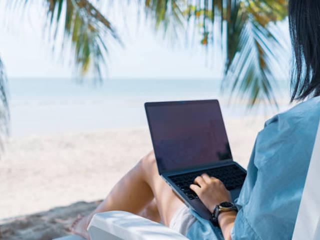 Woman using laptop on the beach