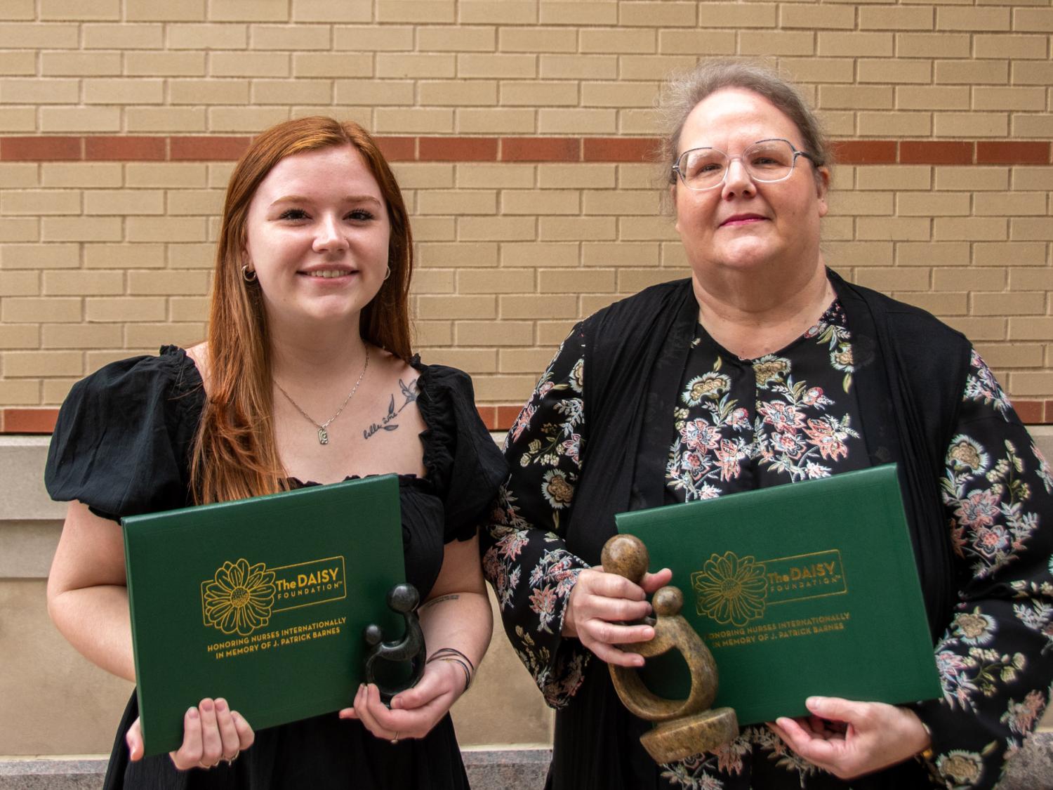 Two people standing together holding awards