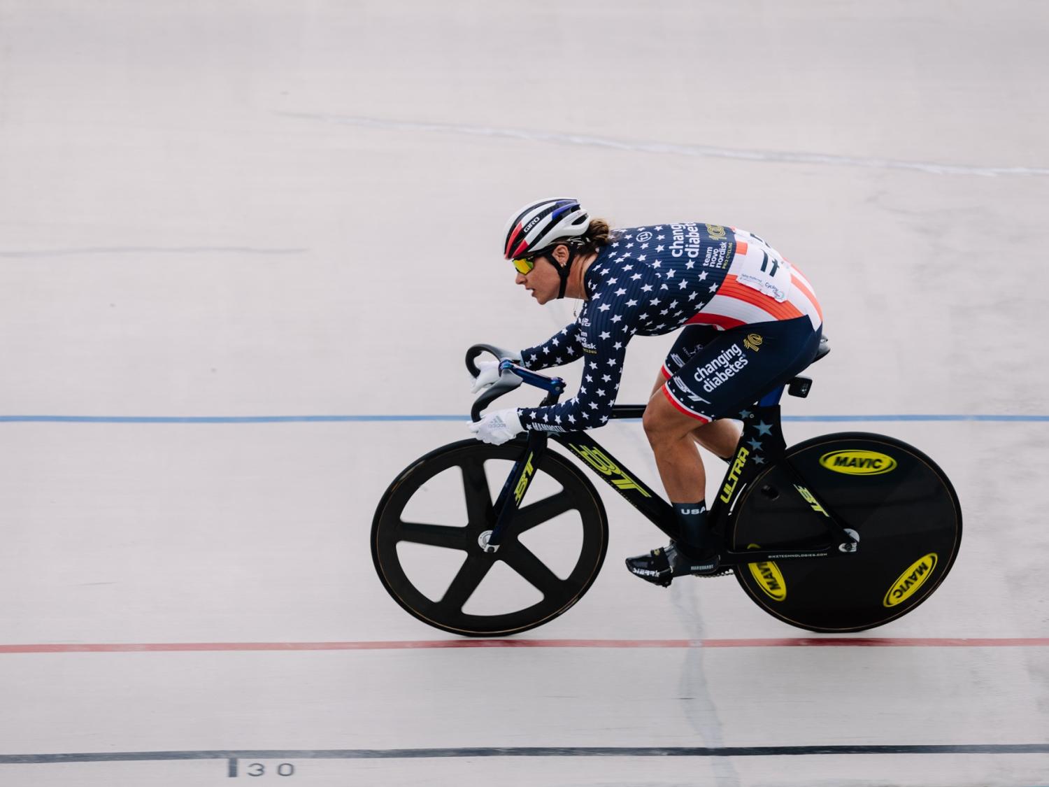 A woman on a bicycle races down a track.