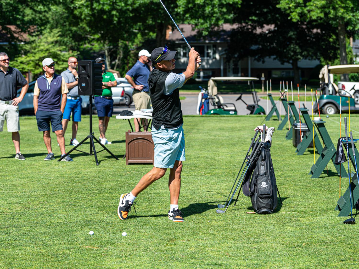 A golfer on the field at a tournament takes a swing.