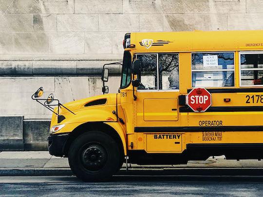 Yellow school bus outside of a school.