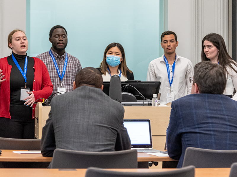 Students standing behind podium in front of classroom