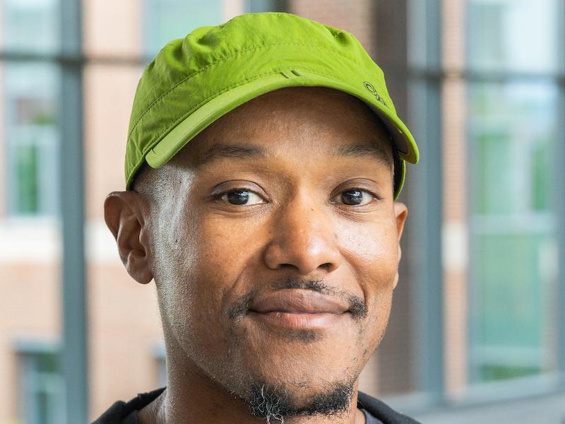 A man looks at the camera wear a green ball cap 