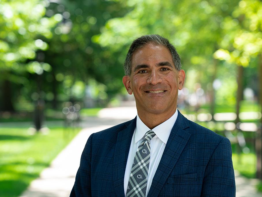Justin Schwartz stands outdoors with green trees in background.