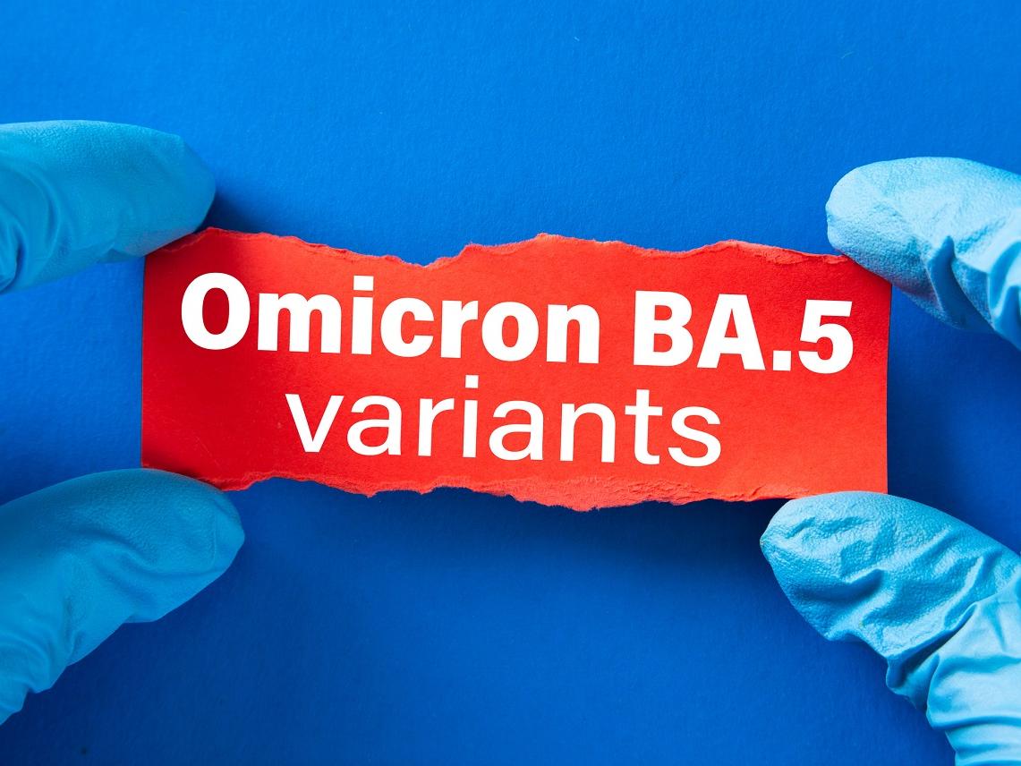 Doctor's hands in blue gloves hold writing on torn paper that says “Omicron BA.5 variants.”