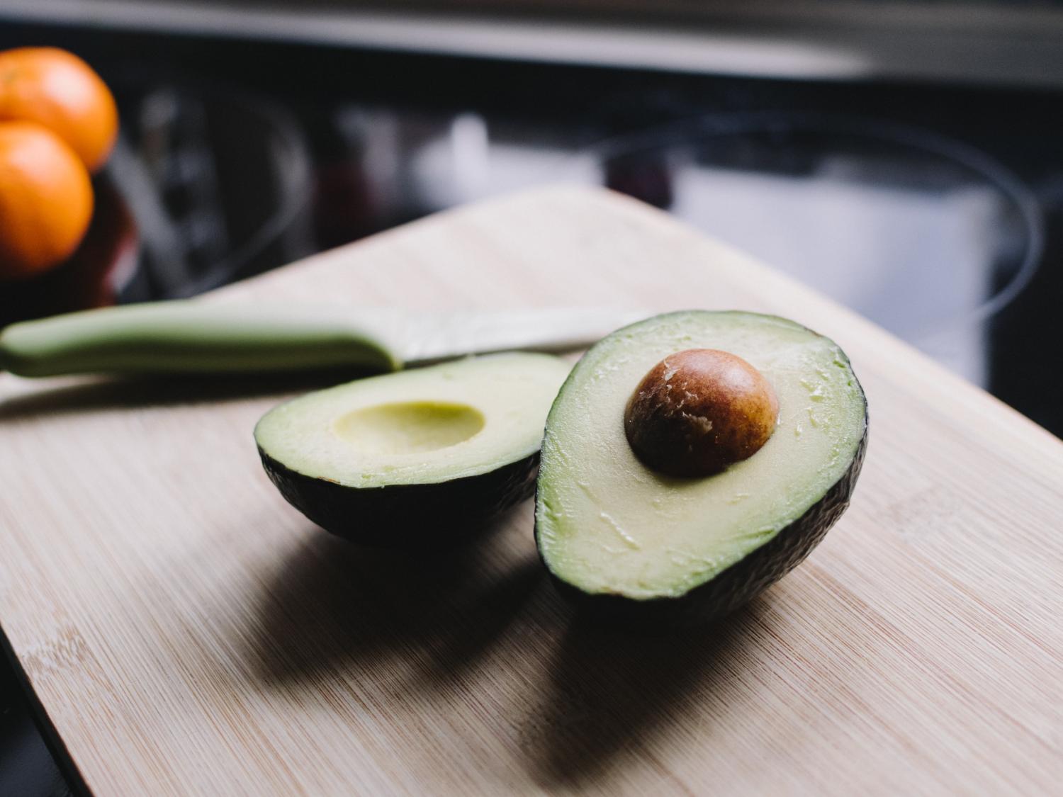 An avocado cut in half and lying on a cutting board
