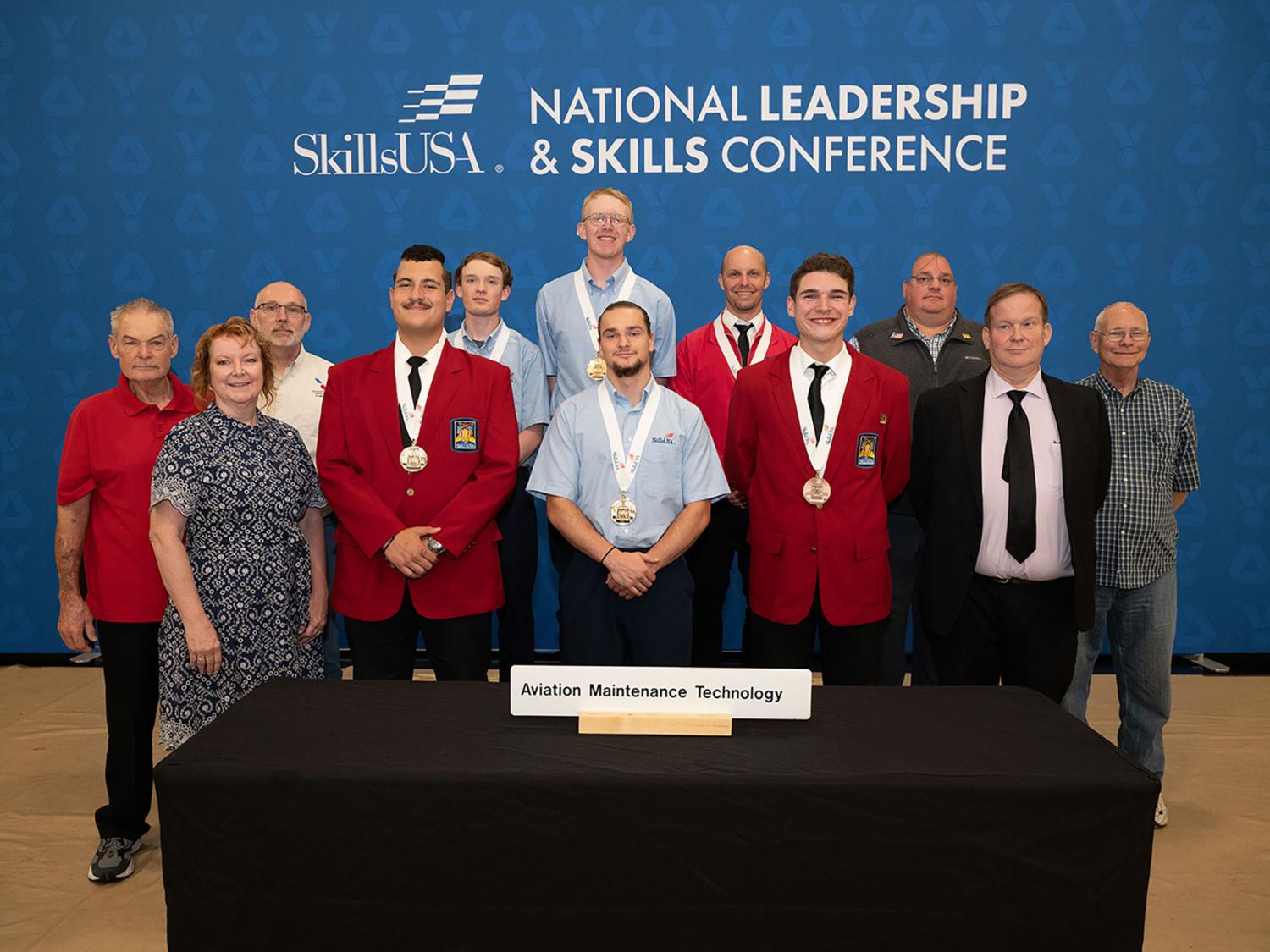 A group of award winners, some with medals draped around their necks, against a blue backdrop with the words "SkillsUSA National Leadership & Skills Conference."