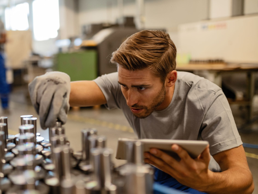 A student inspects some metal items, holding clipboard and using globe