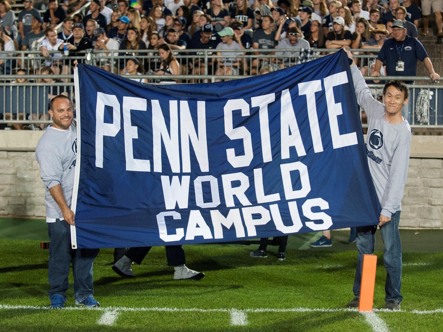 Two students hold World Campus banner at All-U Day