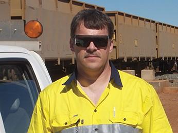 Warren Fargo, a Penn State Behrend graduate, stands in a railyard.