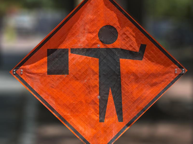 An orange construction sign showing a flagger