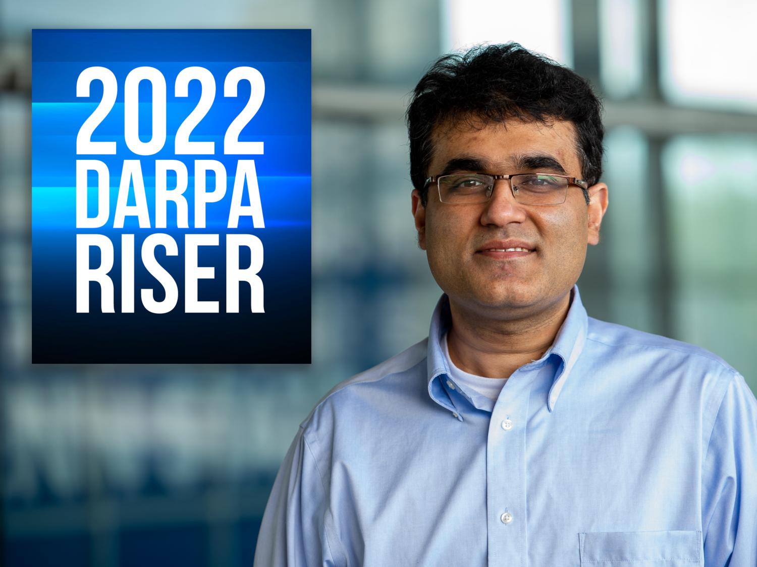 dark-haired man in blue dress with award photo caption