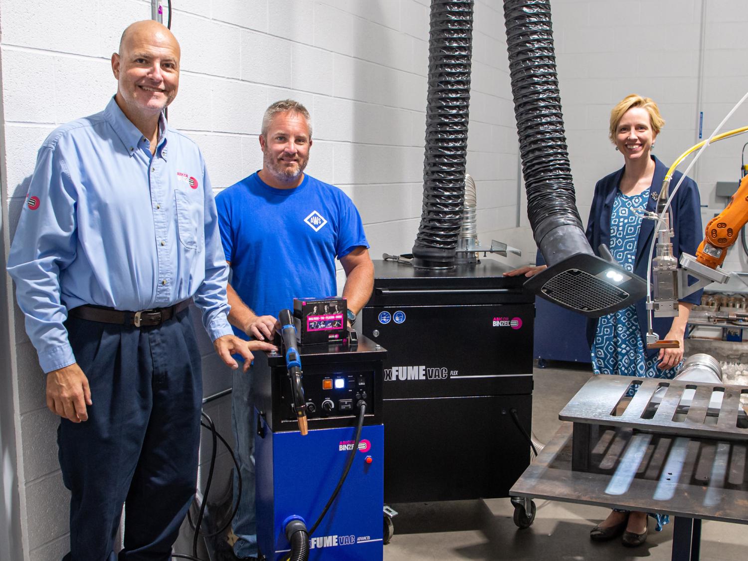 Abicor Binzel company representative stands next to donated welding equipment with assistant professor from Penn College