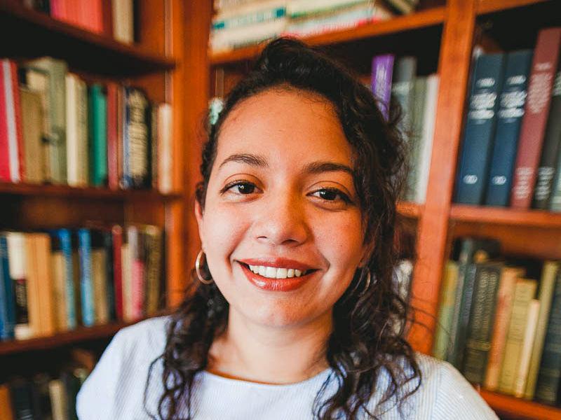 Portrait of woman standing in front of bookshelves