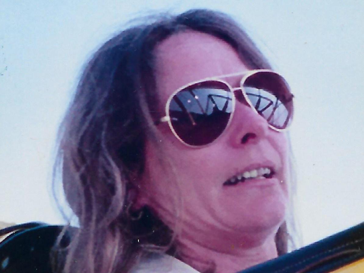 An image of Brenda Saylor wearing sunglasses as she sits in a yellow airplane