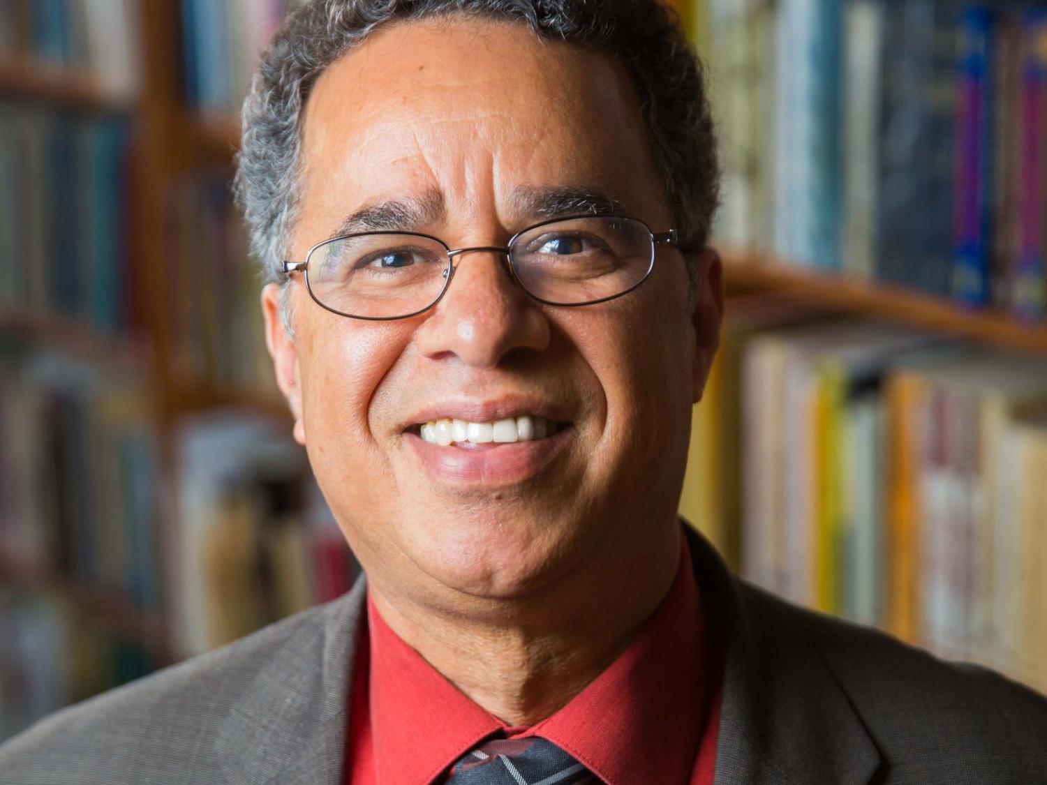 Man in glasses with a red shirt, tie, and suit jacket.