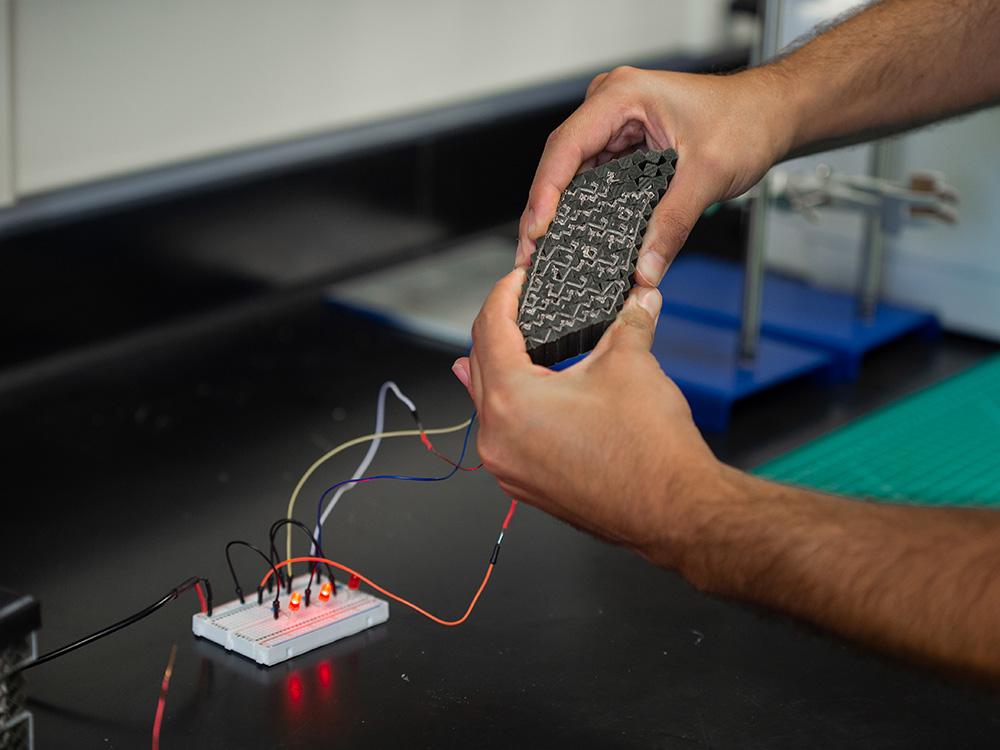 A researcher squeezes the circuit, which compresses in his hands.