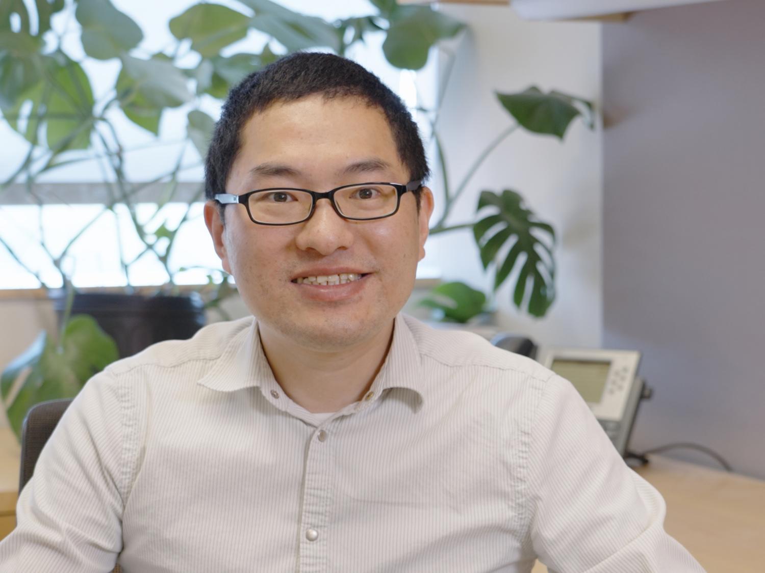 Lance Lian sitting with a plant and a table visible behind him