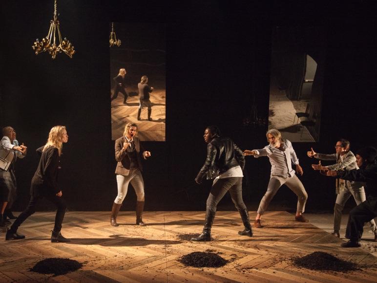 Two groups of people on each side of a stage face each other as if ready to fight.