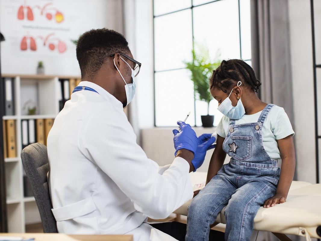 A doctor prepares to give an injection to a young girl.