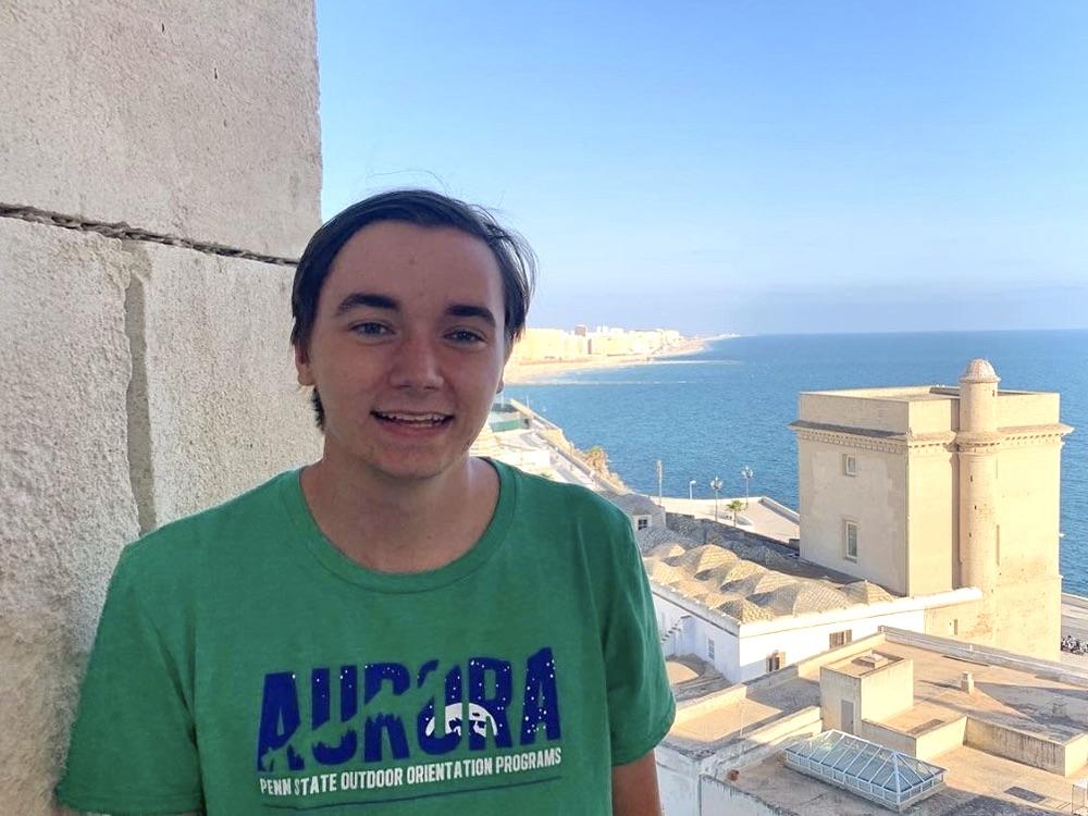 Stevens Gustafson stands in the foreground with the ocean in the background in Cadiz, Spain