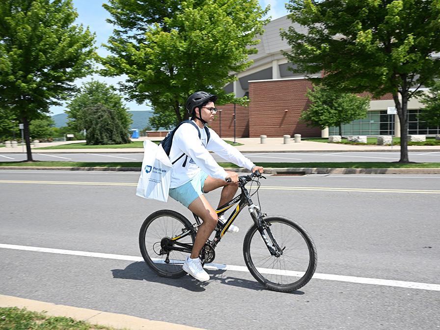 A person riding a bike on the street and wearing a bike helmet