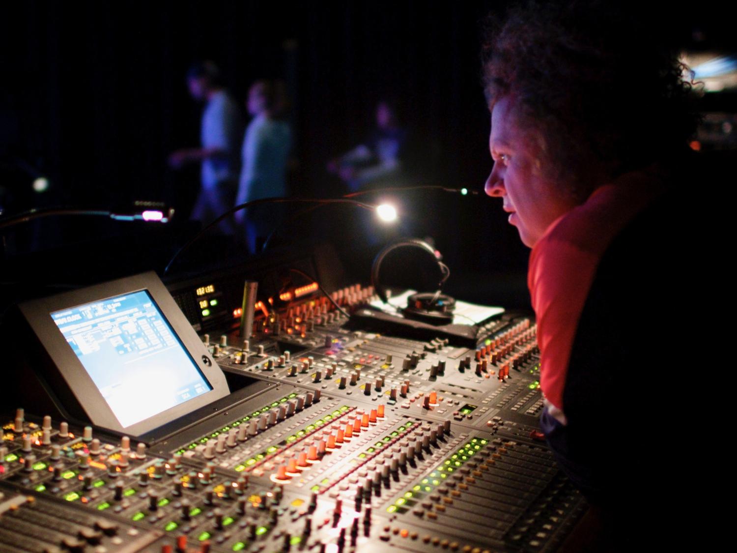 Man leaning over a sound board during a theatre performance