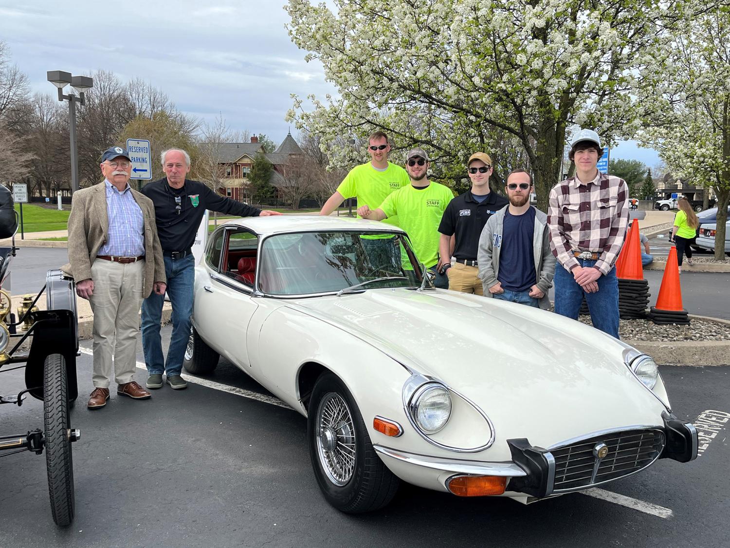 Students surrounding 1973 E-series Jaguar after restoration work.