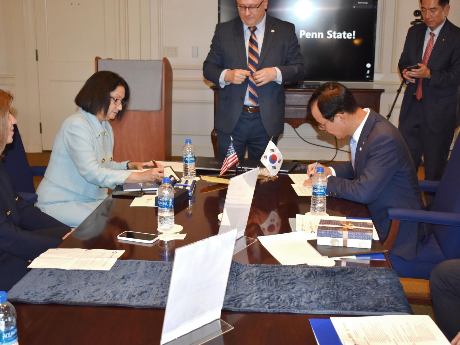 Two university presidents, one male and one female, signing an agreement