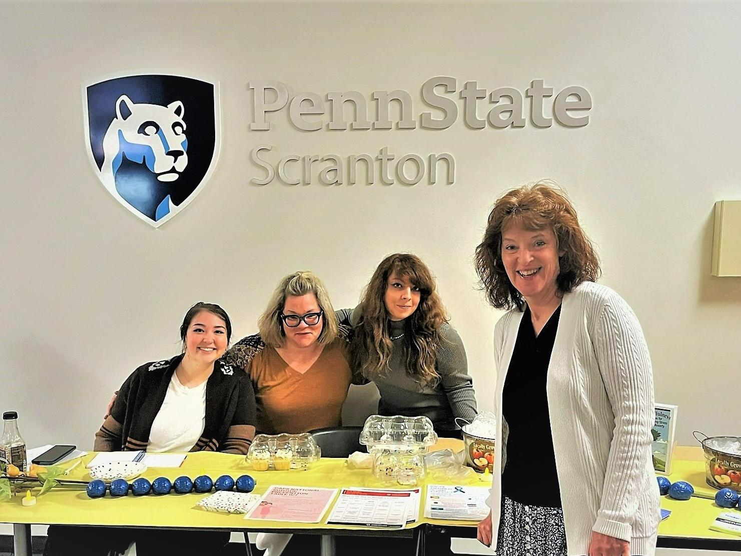 group of staff and students pose for photo at mental health services info table