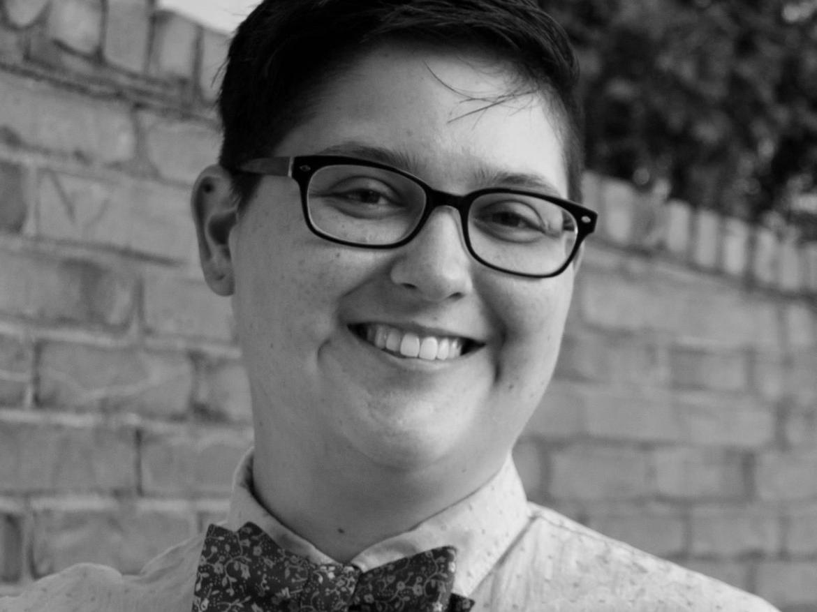 Person with short dark hair and black rimmed glasses