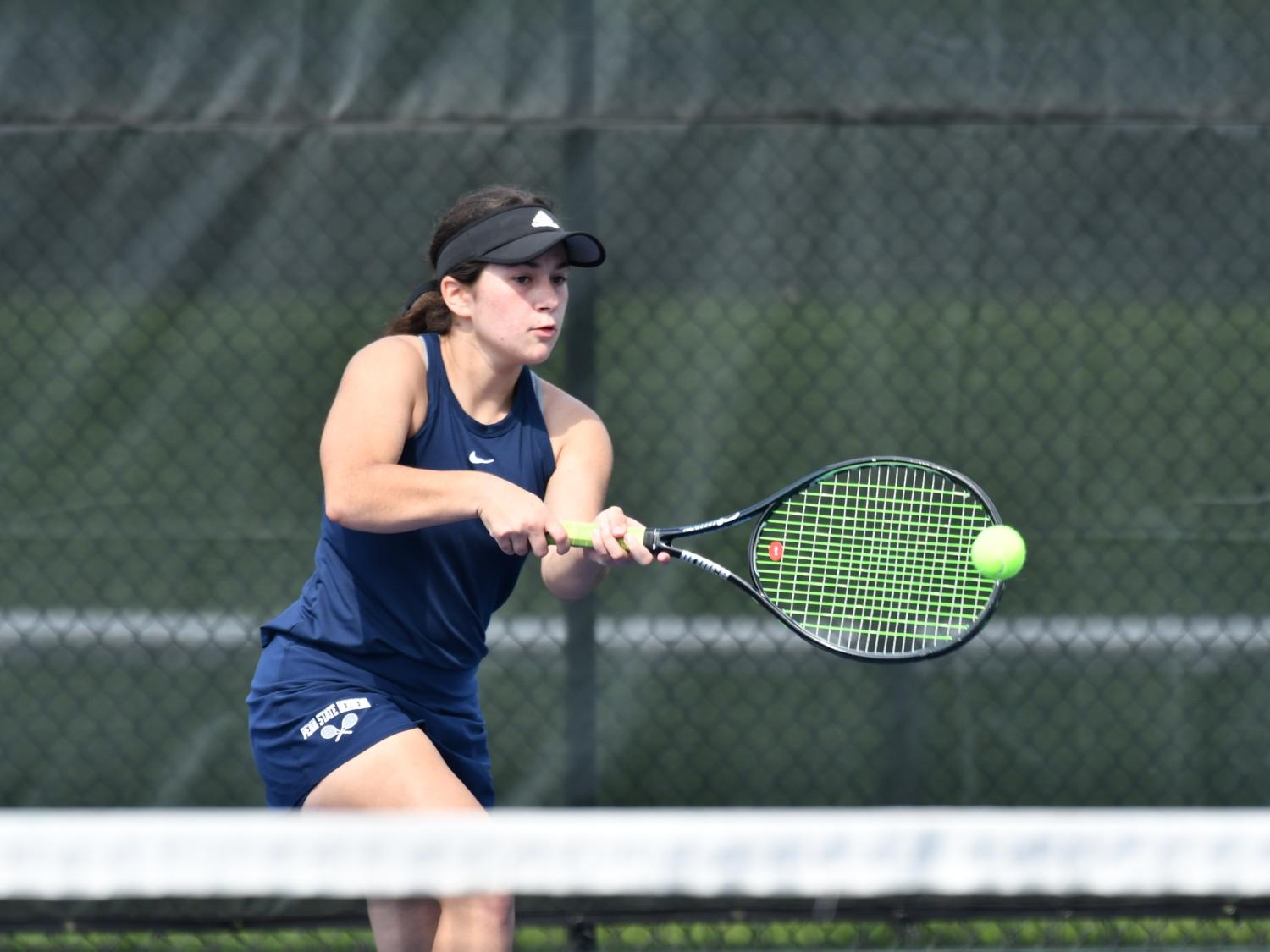 A Penn State Behrend tennis player hits a backhand.