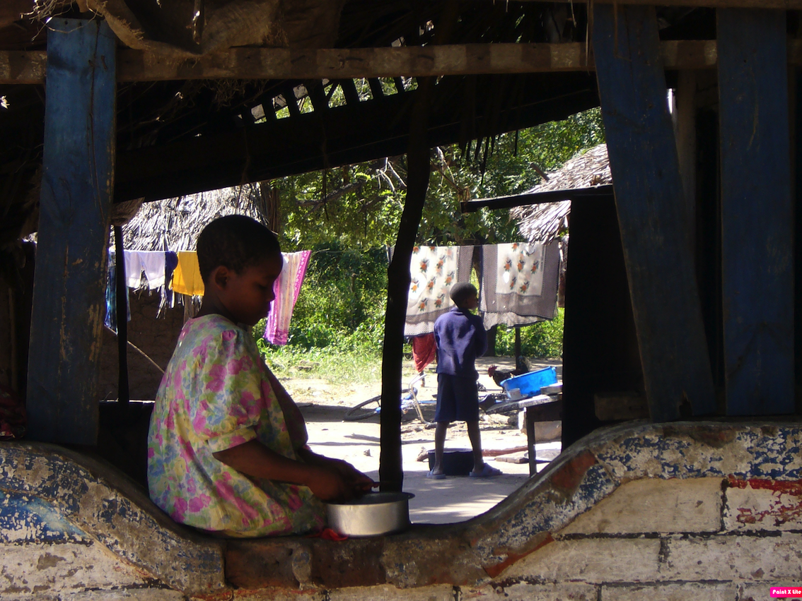 A child sitting on a low wall in Tanzania