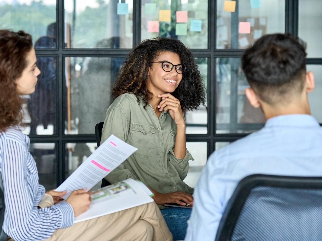 Three teenagers sit in a circle while having a discussion. 
