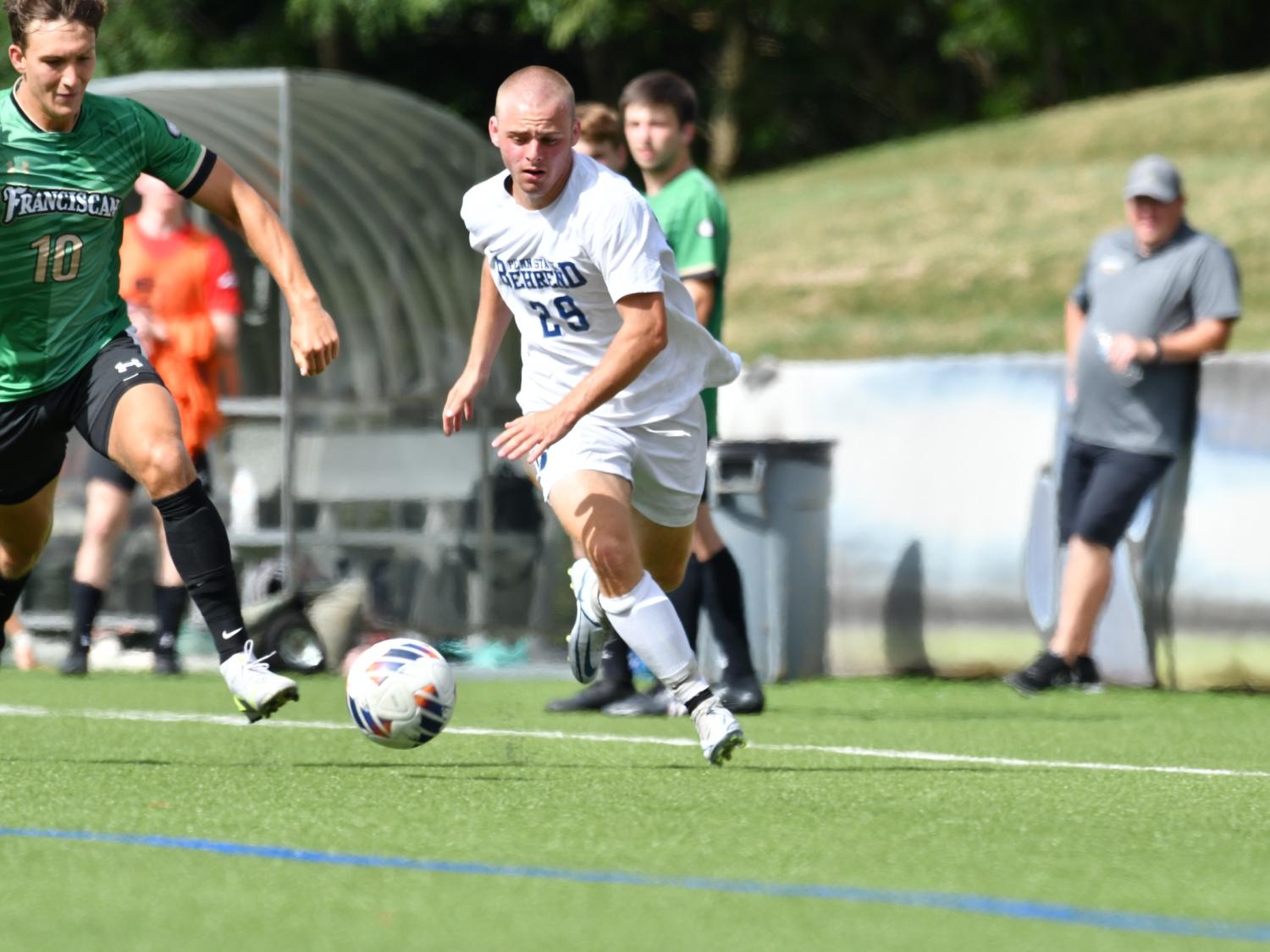 A Penn State Behrend men's soccer player advances the ball up the field.