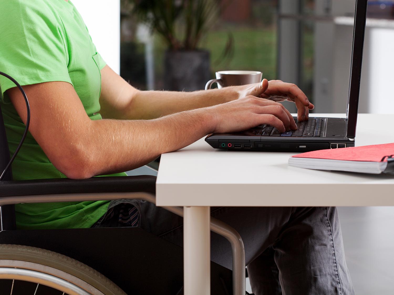 A man in a wheelchair uses a laptop
