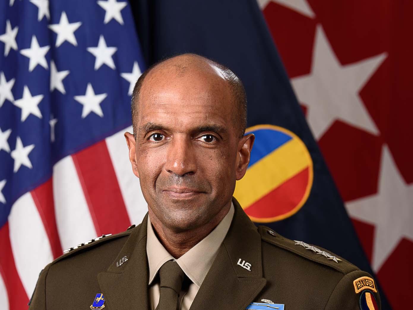 Official portrait of General Gary Brito in uniform in front of three different flags