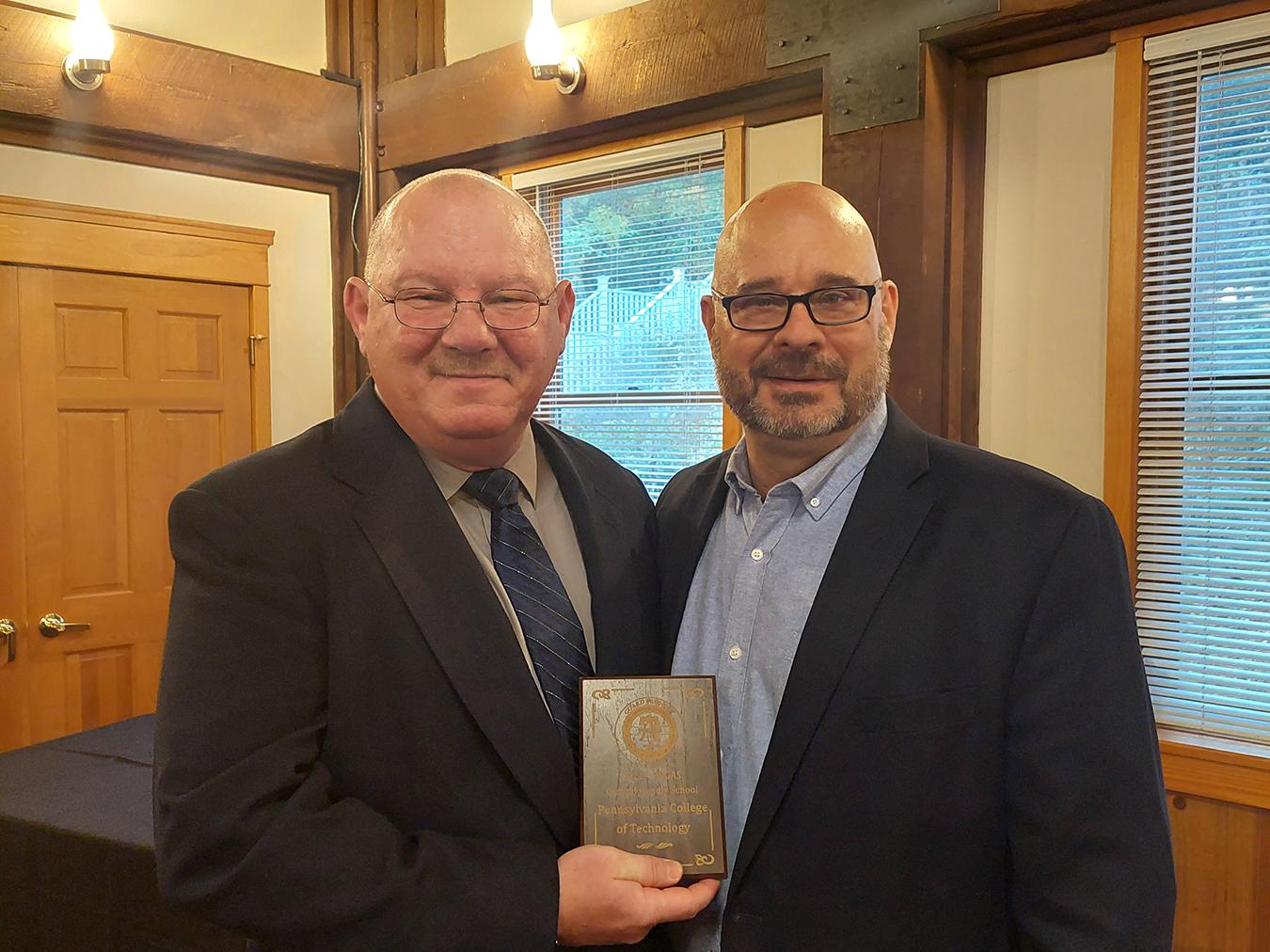 Guy receiving an award on behalf of Penn College
