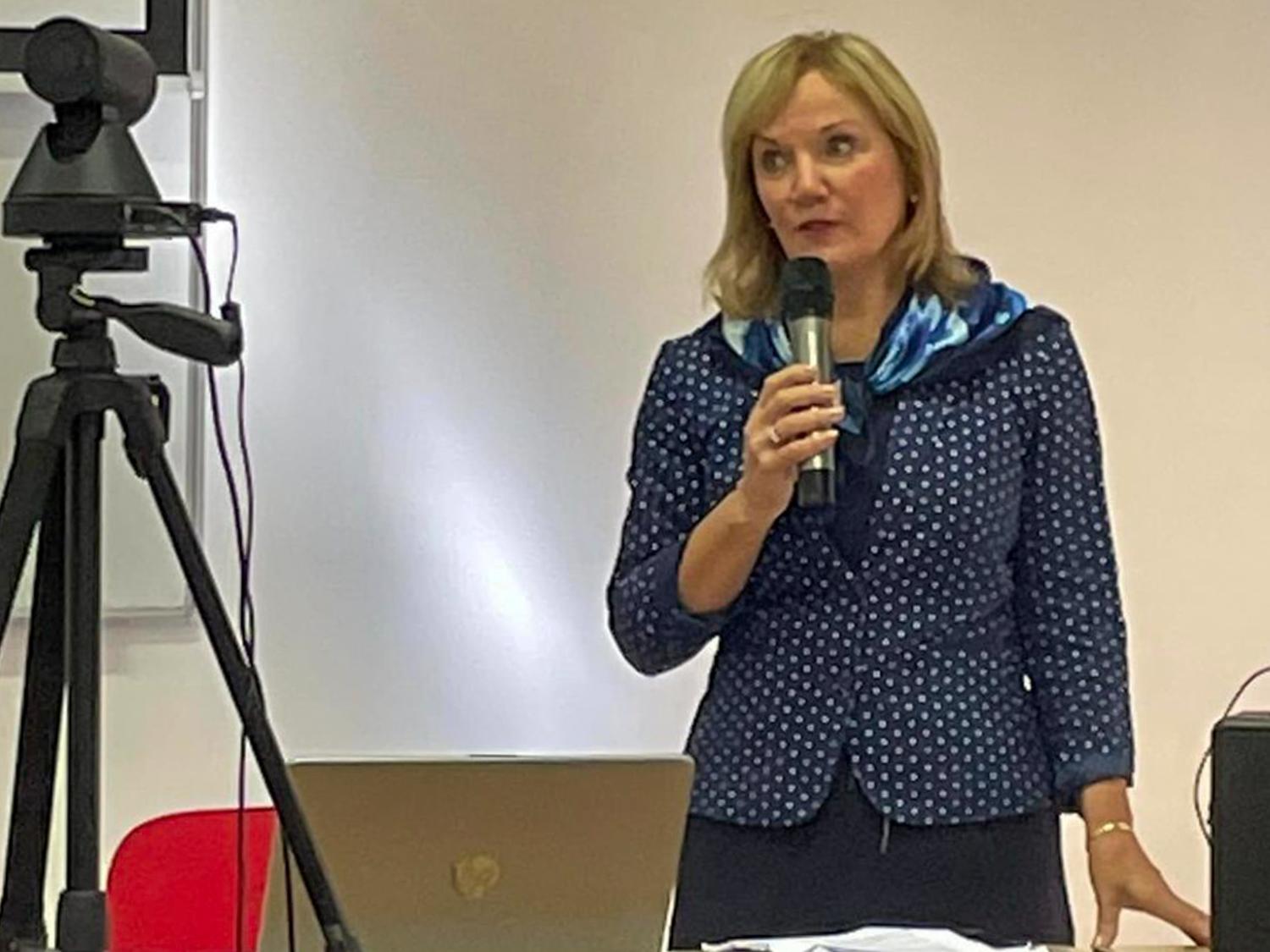Nichola Gutgold at podium speaking with faculty