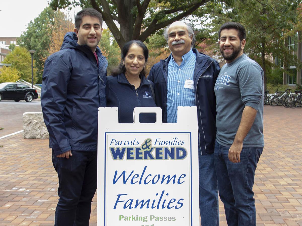 family standing by a parents weekend sign