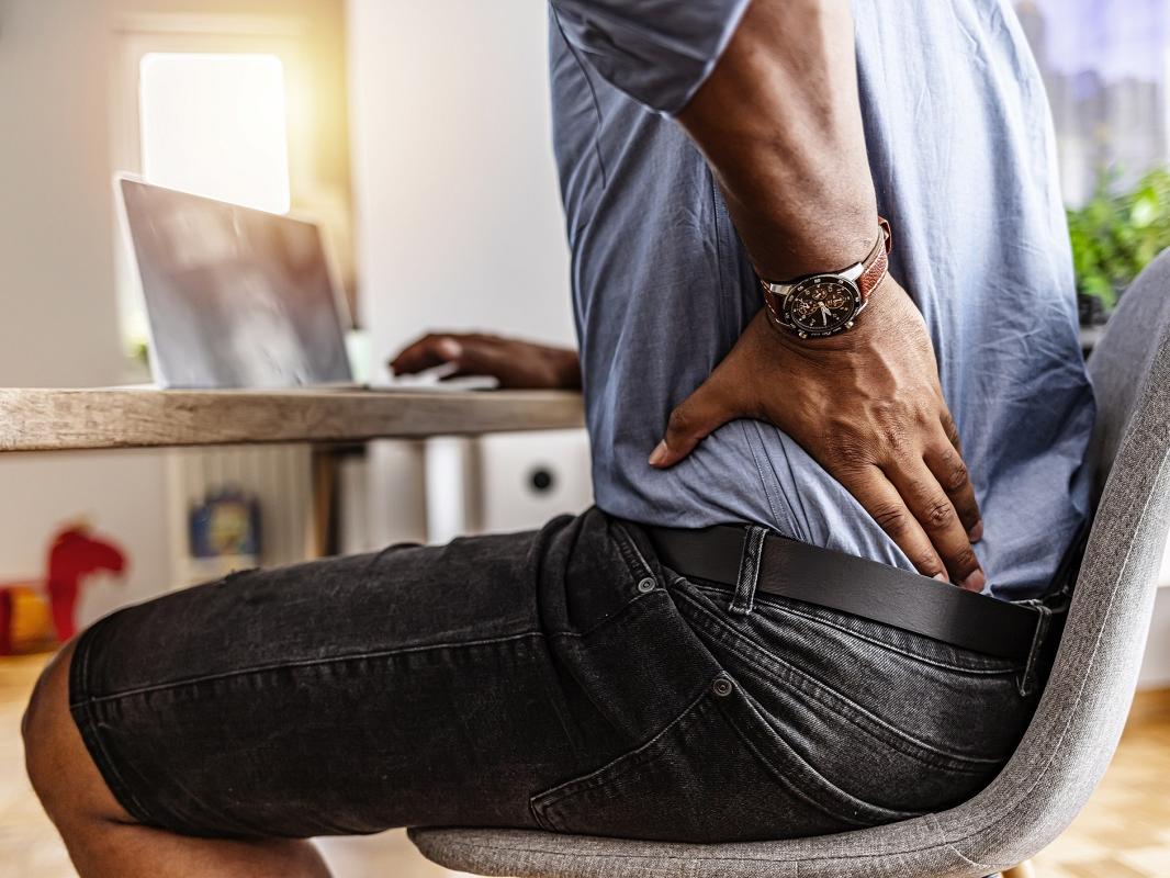 Shot of a young businessman suffering from a backache while working at his desk in his office.