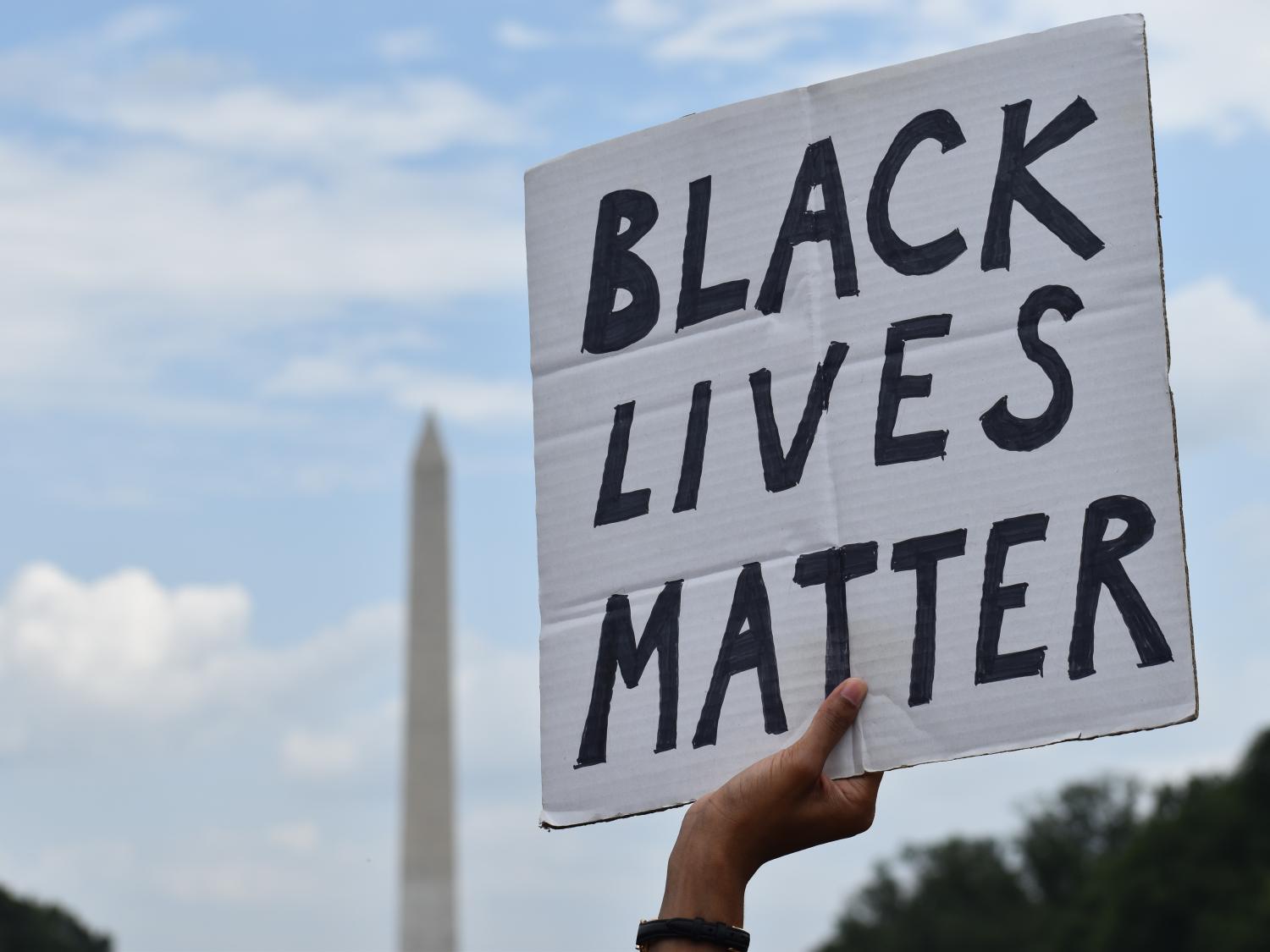 A hand holding up a sign reading Black Lives Matter