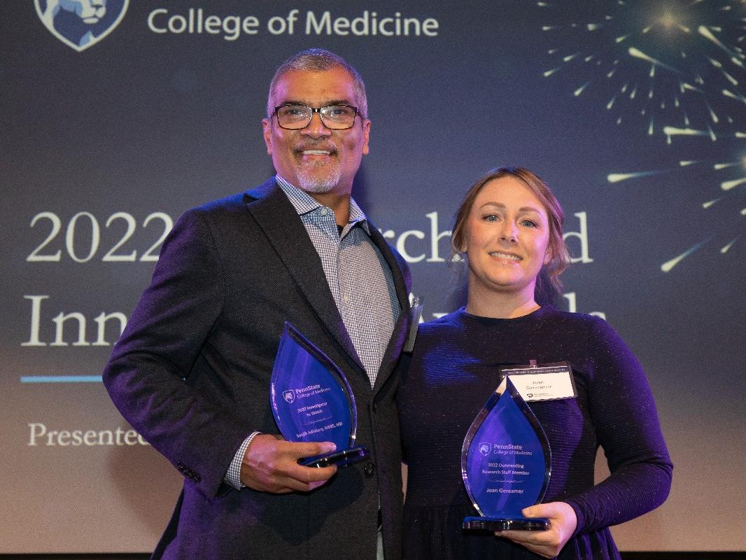 Award recipients and Joan Gensamer stand beside each other while holding their award trophies. 