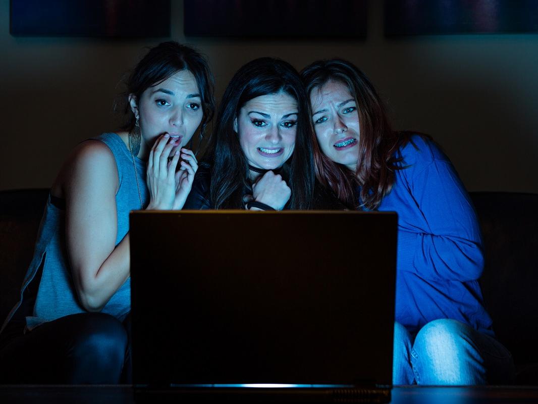 Three girlfriends, watching something scary on a laptop computer. 
