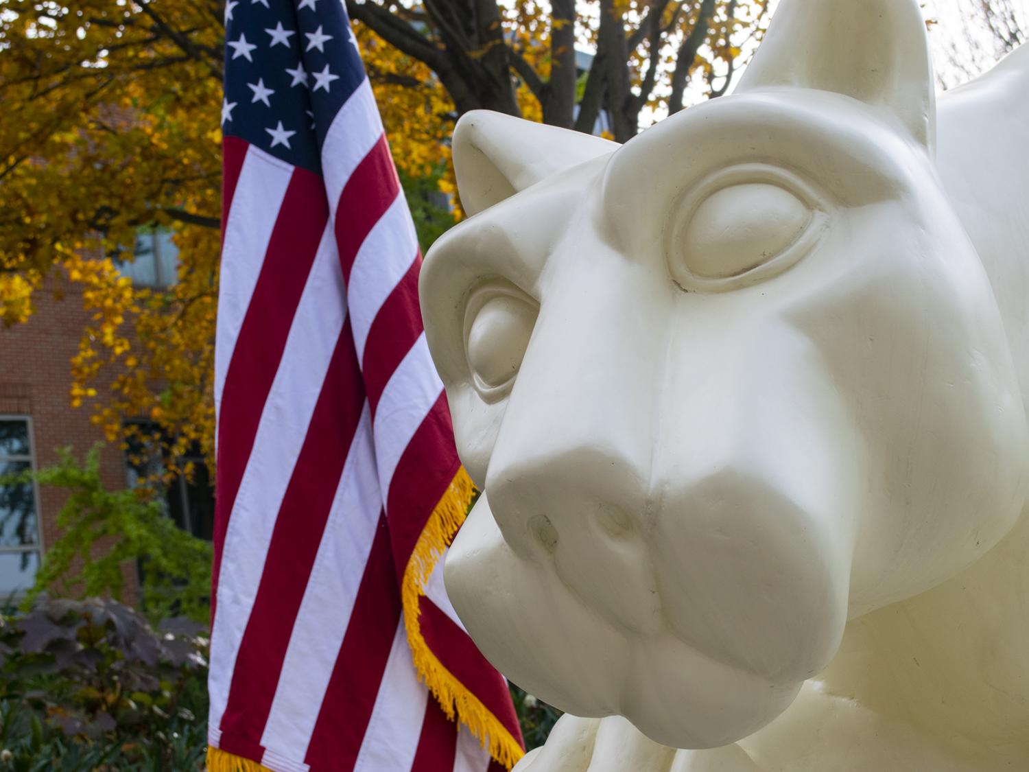 Photo of a U.S. flag next to the Nittany Lion statue 