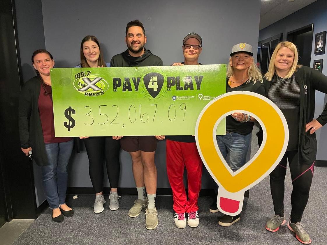 Six people pose with a banner touting the dollar amount $352,067.09.