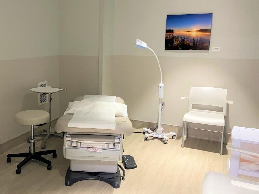 A clinic room with an exam chair, computer and various medical equipment.